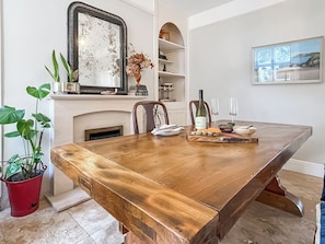 A dining area with a wooden table, chairs, a fireplace, and a mirror. - 3 bedroom accommodation in Torquay (Torquay)