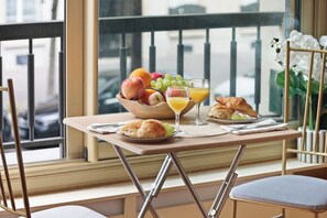 Ein Frühstückstisch mit Früchten, Saft und Croissants auf einem Balkon mit Blick.