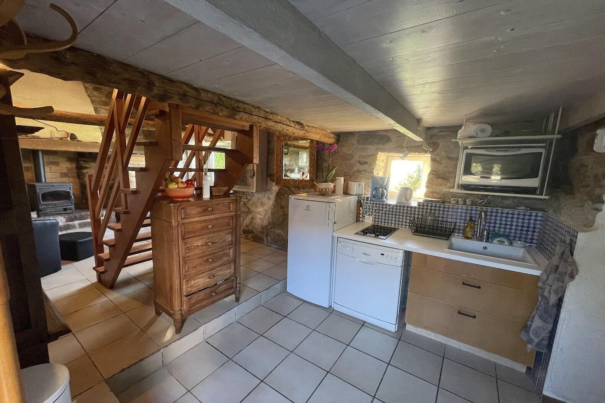 A rustic kitchen with a wooden staircase, a white refrigerator, a microwave, and a tiled backsplash.