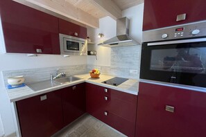 A kitchen with a microwave, oven, and a bowl of fruit on the counter. - Rental for 2 with Private Outdoor Space (Plougasnou)