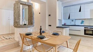 Eine moderne Küche mit weißen Schränken, einer Steinsäule und einem Essbereich mit einem Holztisch und Stühlen.