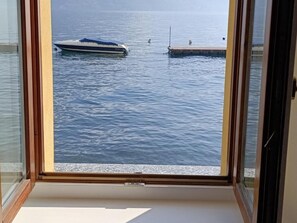 Une vue à travers une fenêtre sur une étendue d’eau, avec un bateau et un quai.