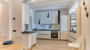 Eine moderne Küche mit weißen Schränken, einer schwarzen Arbeitsplatte und einem Holzespeisetisch mit Stühlen.