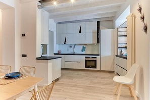 A modern kitchen with white cabinets, a black countertop, and a wooden dining table with chairs. - Aqua Vista di Splendore (Argegno)