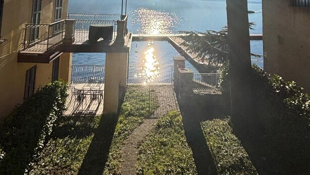 Ein Gebäude mit Balkon, das auf ein Gewässer und entfernte Berge blickt.