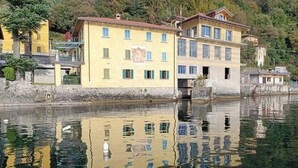 Ein mehrgeschossiges Gebäude mit Balkonen, einem Spiegelbild im Wasser und freiem Blick auf die umliegende Landschaft.