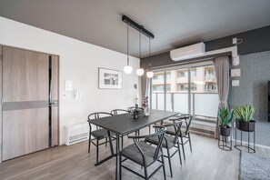 Un comedor moderno con una mesa, sillas, lámparas colgantes y plantas en macetas.
