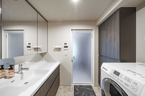 A modern bathroom with a double sink, a mirror, a washing machine, and a frosted glass door. - JAPAVISTA Noir 703 (SAPPORO, CHUO WARD,)