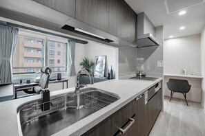Una cocina moderna con una isla grande, electrodomésticos integrados y vistas a un edificio residencial.