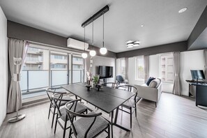 A modern living room with a dining area, large windows, a flat-screen TV, and a sofa. - JAPAVISTA Noir 703 (SAPPORO, CHUO WARD,)