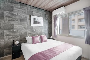 A modern bedroom with a large bed, a nightstand, an air conditioner, and a window with curtains. - JAPAVISTA Noir 703 (SAPPORO, CHUO WARD,)