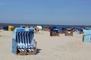 Strandliegen und Sonnenschirme am sandigen Strand.