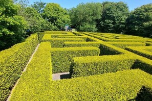 A meticulously landscaped garden with geometric hedge patterns and a small pavilion in the background. - Holiday home in Norden with swimming pool (Norden)