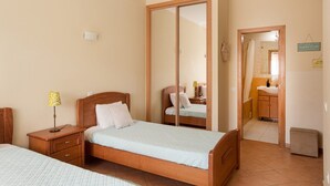 A bedroom with a bed, bedside table, lamp, wardrobe, and a bathroom visible through an open door. - Central Albufeira Stay Balcony AC (Albufeira)