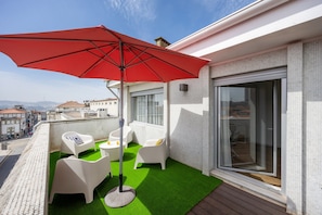 A balcony with a red umbrella, white chairs, a small table, and a green artificial turf. - Blue Terrace Porto (Porto)