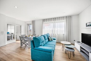 A modern living room with a blue sofa, a dining table, and a TV. - Blue Terrace Porto (Porto)
