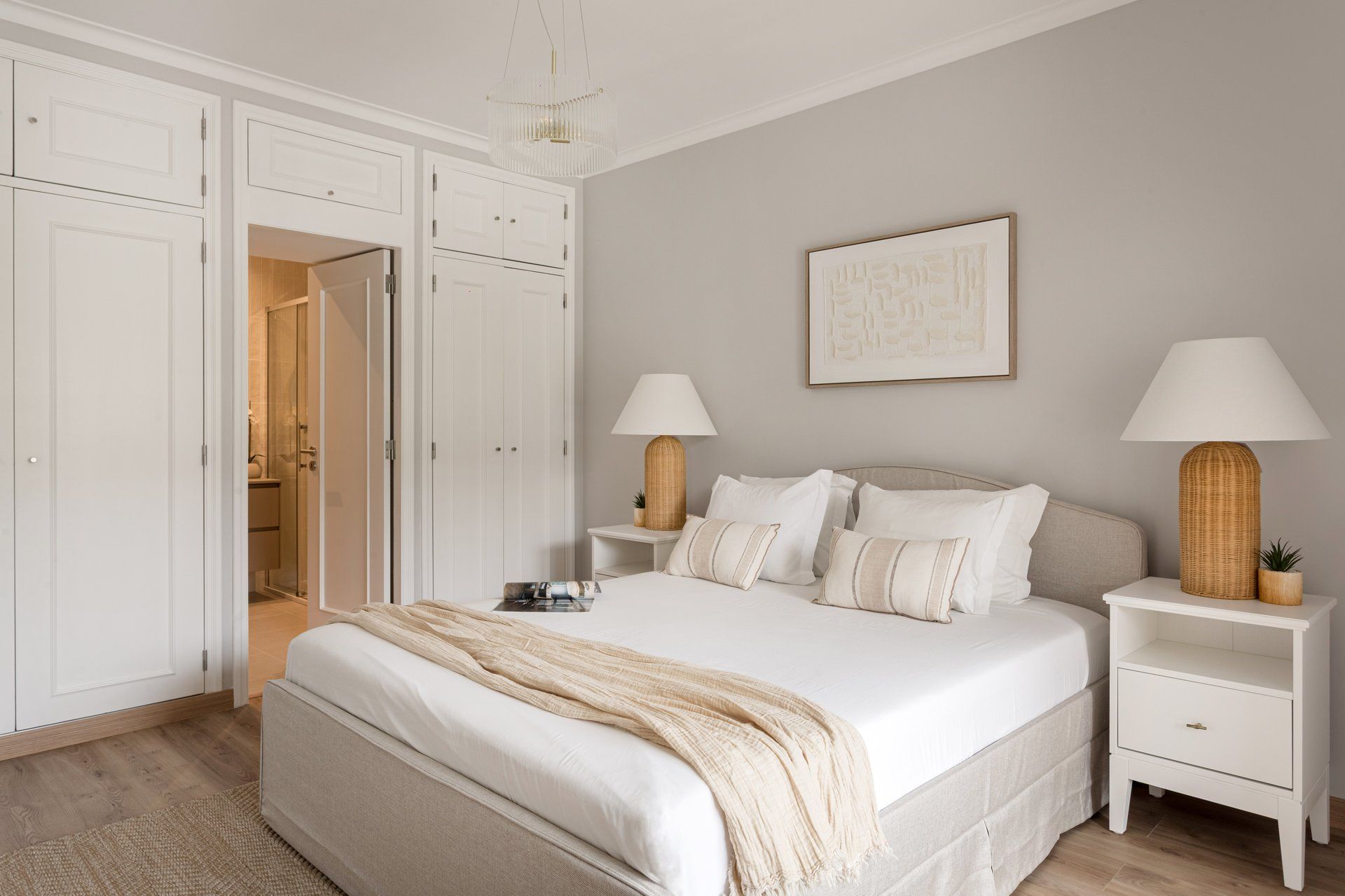 Een slaapkamer met een bed, nachtkastjes, een lamp, een kledingkast en een lijst aan de muur.