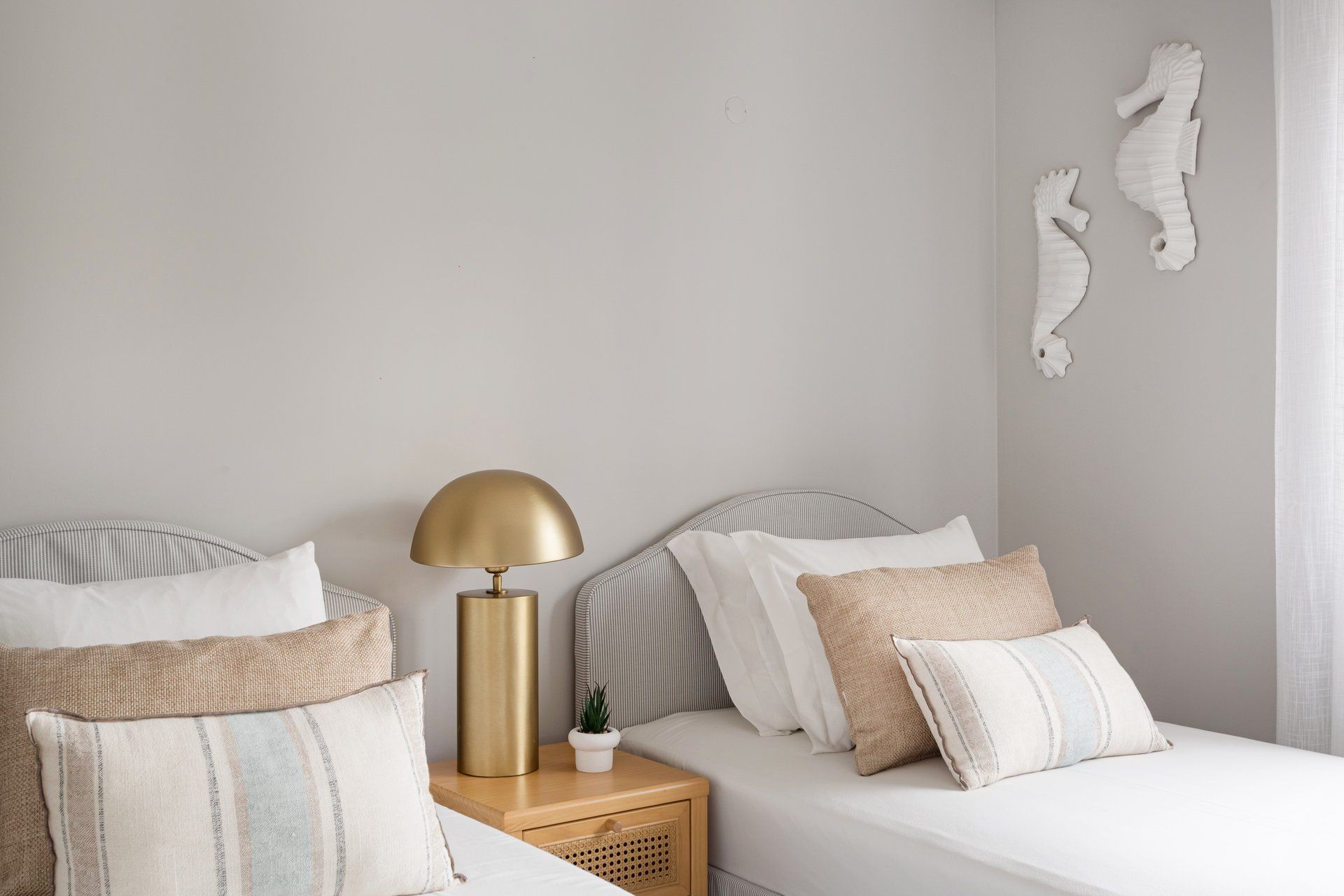 A bedroom with two beds, a bedside table with a lamp, and decorative wall art.