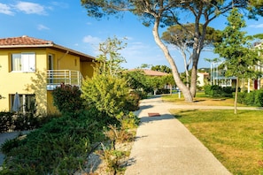 A yellow building with a balcony, surrounded by greenery and trees. - Côte d'Azur Chic Apartment for 4 (Six-Fours-les-Plages)