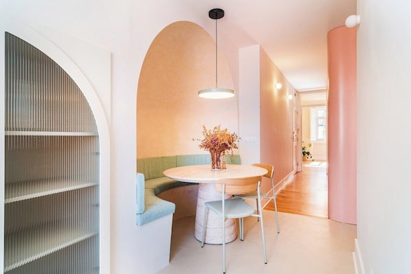Ein modernes Interieur mit einem runden Tisch, einem grünen Sofa und einem großen Bogenfenster.