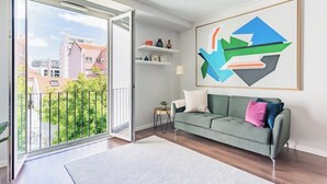 Ein modernes Wohnzimmer mit einem grünen Sofa, einem weißen Teppich und einem großen abstrakten Gemälde an der Wand.