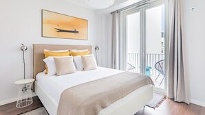 Ein Hotelzimmer mit Bett, einem Gemälde, einem Balkon und Blick ins Freie.