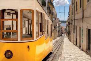 A yellow tram on a cobblestone street with buildings on either side. - Vintage Inspired Flat in Lisbon (Lisbon)