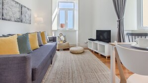 Un soggiorno moderno con divano, televisore e zona pranzo con tavolo e sedie.