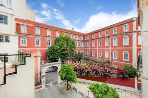 Ein Innenhof mit einem roten Gebäude, einem Baum und einem Blumenbeet.