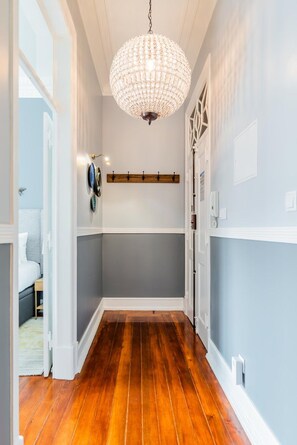 A hallway with a wooden floor, a chandelier, and a coat rack. - Stylish 2BR Apartment Ideal for Monthly Stays (Lisbon)