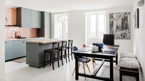 Een moderne keuken met een centraal eiland, een eethoek met stoelen en een groot raam.