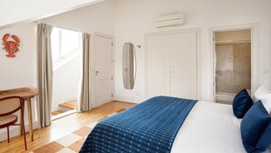 A bedroom with a bed, a desk, a chair, a mirror, and a shower. - Baixa Rooftop Duplex Lisbon (Lisbon)