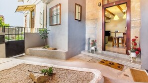 A building with a stone facade, a wooden door, and a small outdoor seating area with a table and chairs. - Gaia Stone House (Vila Nova de Gaia)