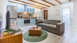 A modern living room with a sofa, coffee table, and a kitchen in the background. - Gaia Stone House (Vila Nova de Gaia)