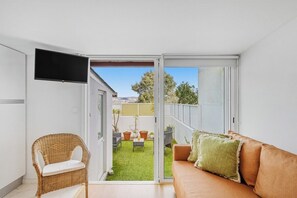 A room with a sliding glass door leading to a backyard, a wicker chair, a sofa, and a flat-screen TV mounted on the wall. - Sunny House With Private Terrace Gaia (Vila Nova de Gaia)