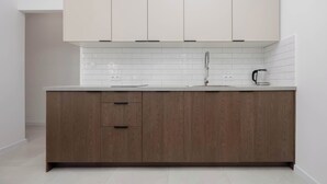 Een moderne keuken met een wit aanrechtblad, houten kastjes en een betegelde spatwand.