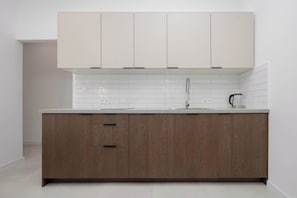 Eine moderne Küche mit weißer Arbeitsplatte, Holzschränken und einer gefliesten Rückwand.