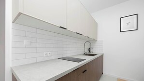 Een moderne keuken met witte metrotegels, een roestvrijstalen spoelbak en houten kastjes.