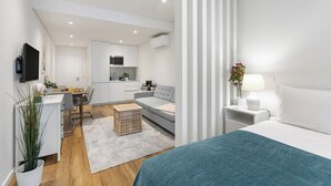 Ein modernes Hotelzimmer mit Bett, Nachttisch und Blick auf die Küche und das Wohnzimmer.