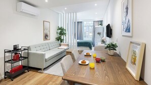 Ein modernes Wohnzimmer mit einer Couch, einem Esstisch und einem Fernseher.