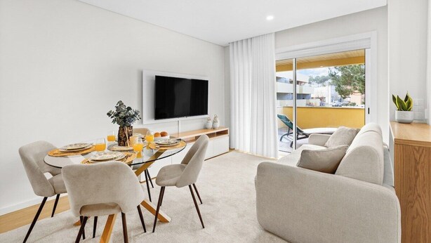 A modern living room with a dining area, a flat-screen TV, and a balcony with a view. - Pinhal do Furadouro Praia Piscina (Ovar)