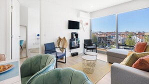 A modern living room with a balcony, a flat-screen TV, and a city view. - Blue Breeze Espinho Pool View, Gym Balcony (Espinho)
