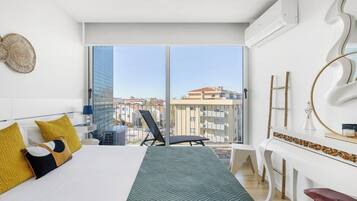 A modern hotel room with a large bed, a balcony with a view, a white console table, and a large window.
