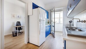 A modern kitchen with white cabinets, a blue accent wall, a built-in oven, a sink, and a window providing natural light. - Charming 3BR w/ Office Garage by Foz Beaches (Porto)