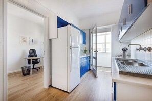 Eine moderne Küche mit weißen Schränken, einer blauen Akzentwand, einem eingebauten Backofen, einer Spüle und einem Fenster für natürliches Licht.