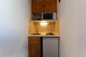 Eine kleine Küche mit Holzausstattung, einer Mikrowelle, einem Spülbecken und einem Geschirrspüler.
