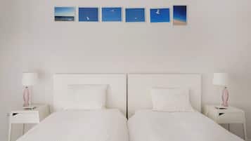 A double bed with white bedding, two bedside tables with lamps, and a wall with five framed pictures.