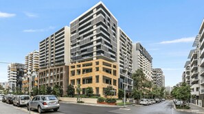 A multi-story residential building with a modern architectural design, featuring balconies and a mix of window styles. - Modern 2BDR Near Airport and Train Station (Mascot)