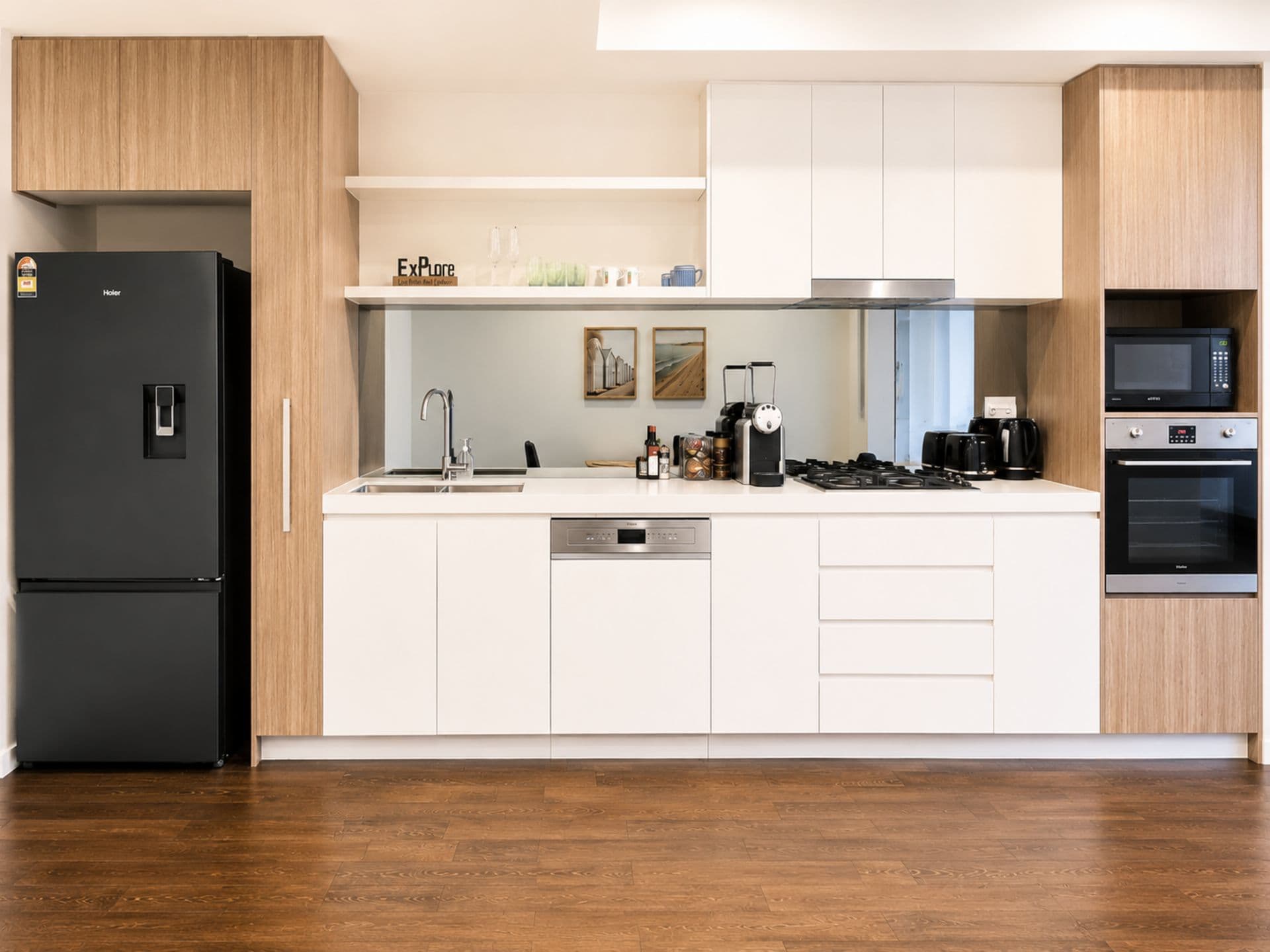 Eine moderne Küche mit einem schwarzen Kühlschrank, einem Geschirrspüler, einer Mikrowelle und einem Backofen.