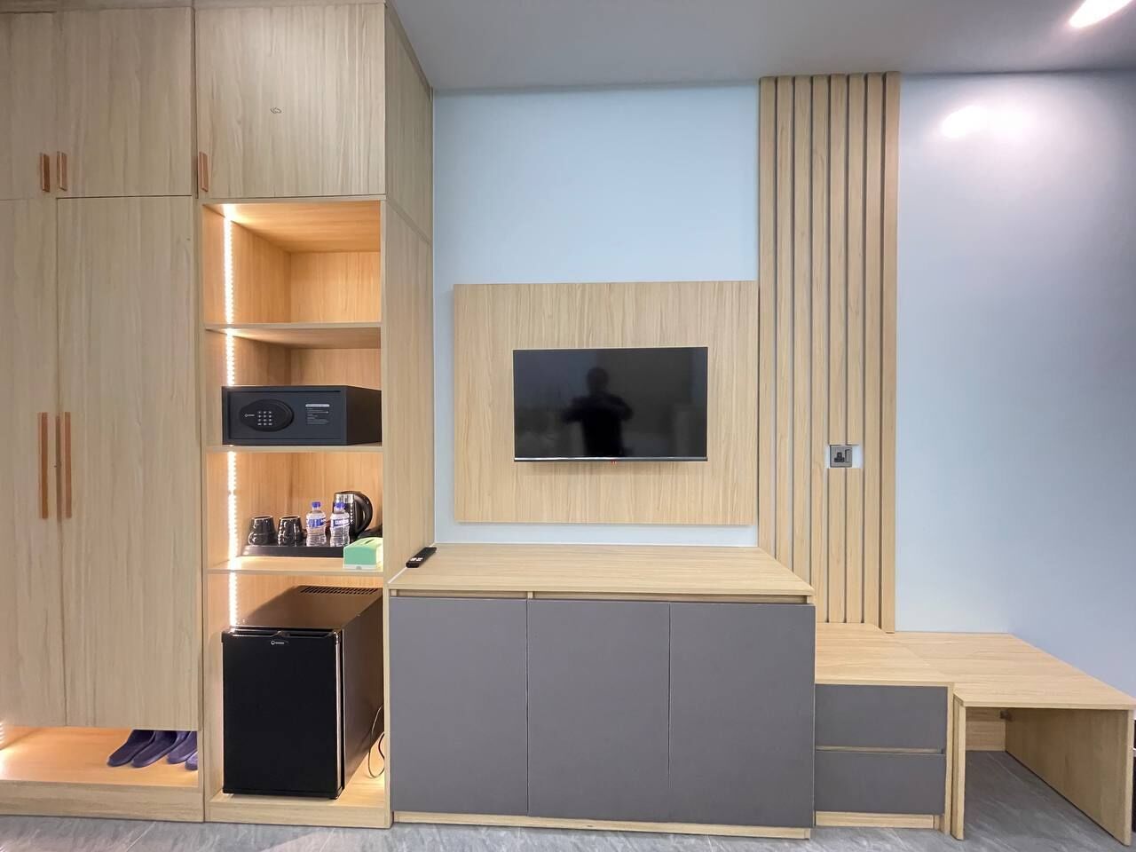 Un espace de vie compact doté de meubles encastrés, d’un téléviseur à écran plat et d’une petite kitchenette.